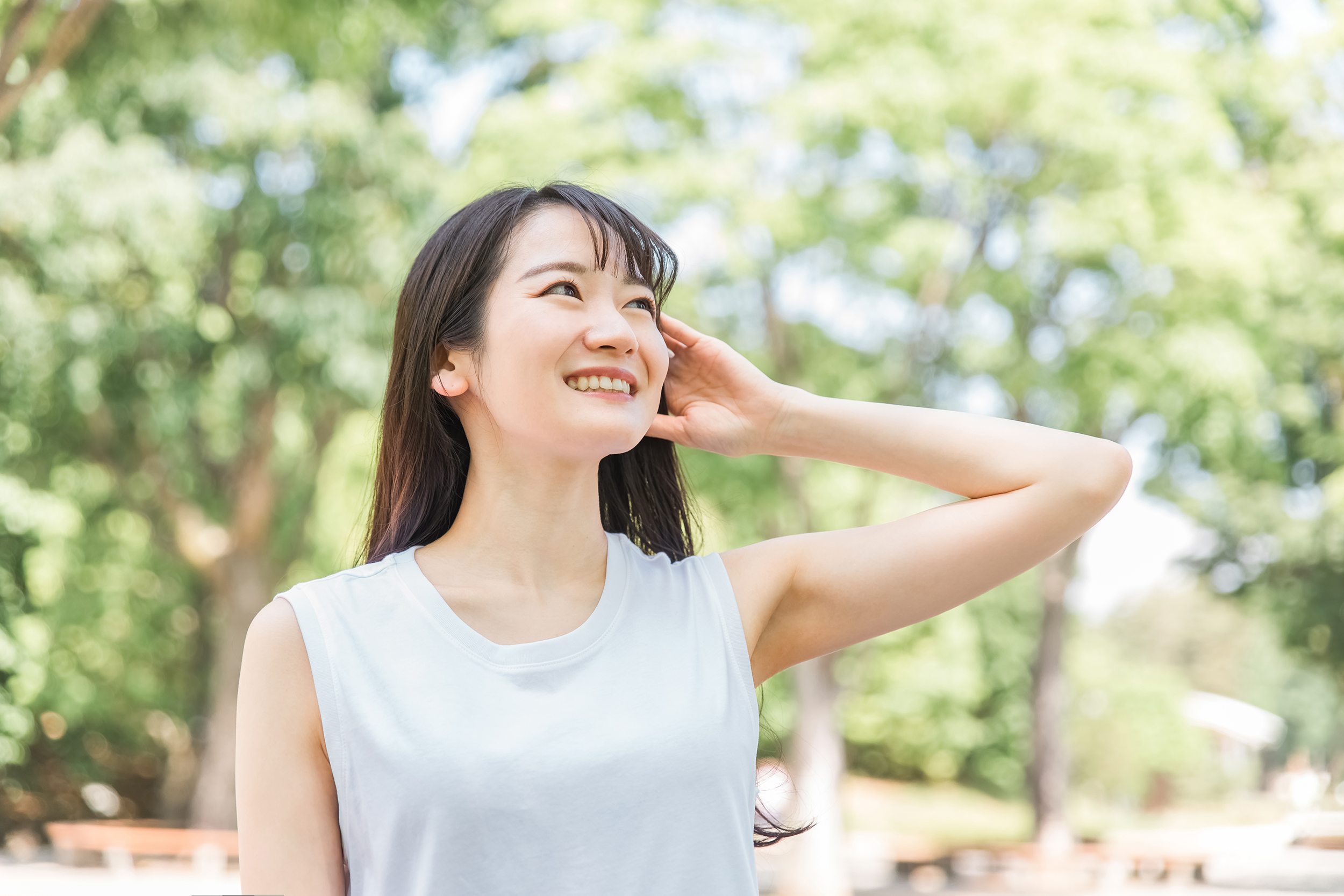 イメージ素材_新緑の中で髪を触る笑顔の日本人女性